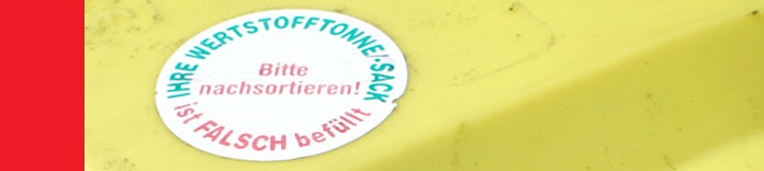 Beanstandungsaufkleber auf einer Gelben Tonne