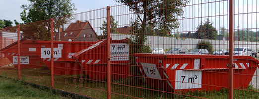 Diverse Absetzcontainer, präsentiert am Zaun des Betriebsgeländes der Hugo-Preuß-Straße